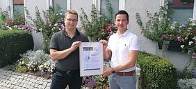 VHS-Leiter Marcel Gutekunst (l.) und Bürgermeister Roman Waizenegger mit dem ZBQ-Siegel; Bildquelle: Gemeinde Bisingen